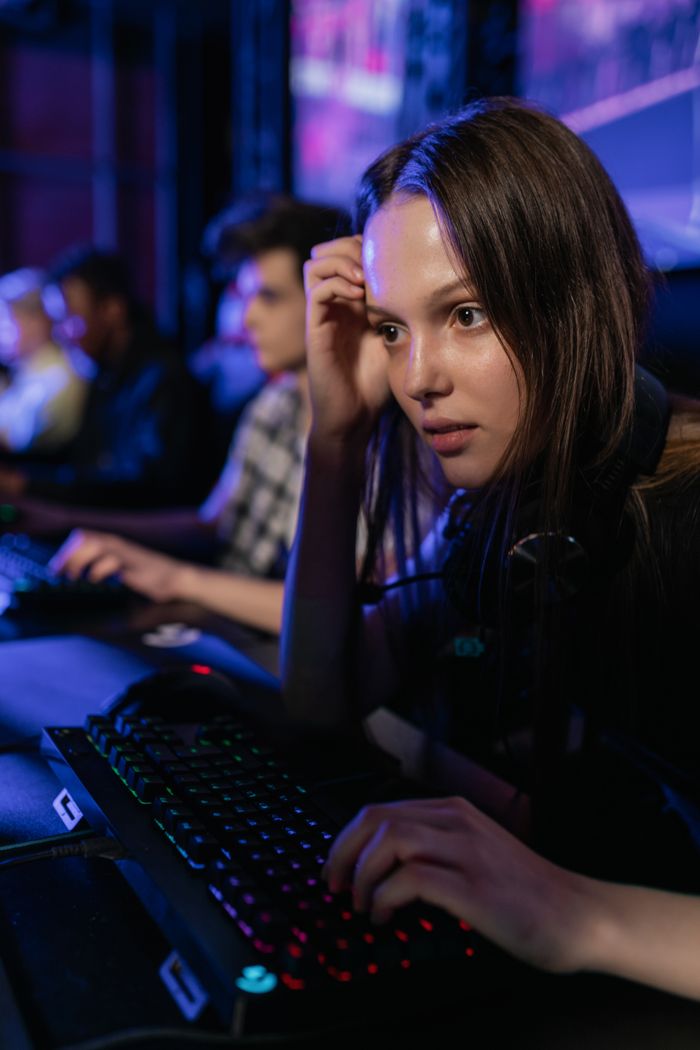 Young Caucasian woman intently gaming at a computer during an esports event, emphasizing focus and intensity.